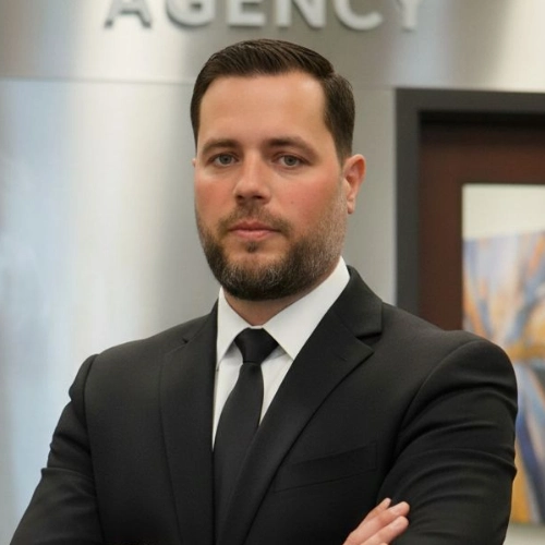 Professional private investigator in a black suit and tie stands confidently with arms crossed in an office, "AGENCY" behind him.