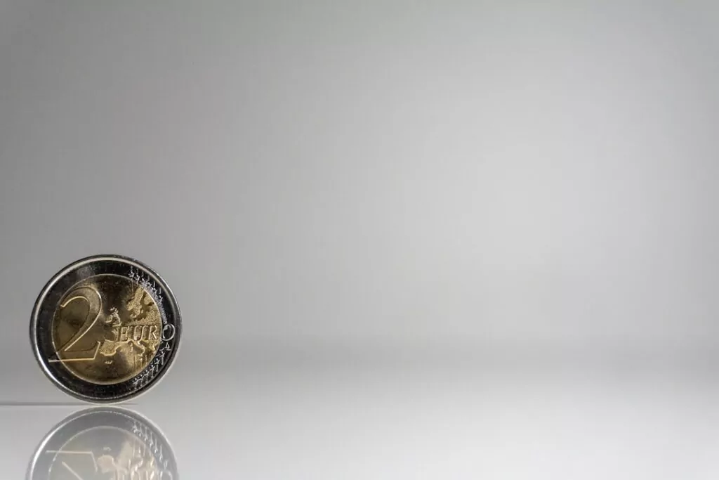 A two euro coin stands upright on a reflective surface, symbolizing value and trust—qualities vital for a top private investigator.